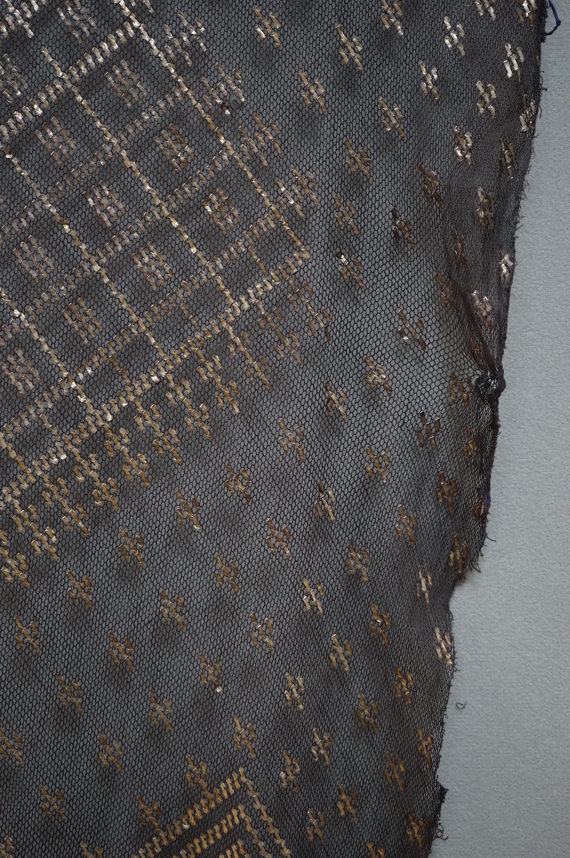 A 1930’s Egyptian decorative metal on black net evening stole. Approximately 218cm long. Condition - the rolled edges are frayed but the colour and design are intact.